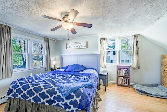 bedroom with a textured ceiling, ceiling fan, wood-type flooring, and vaulted ceiling