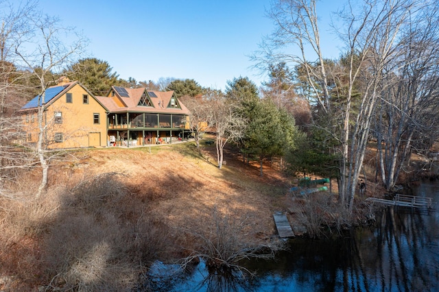 back of property featuring a water view and a sunroom