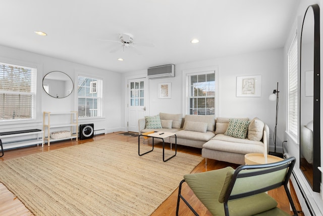 living room with an AC wall unit, ceiling fan, a baseboard radiator, and hardwood / wood-style flooring