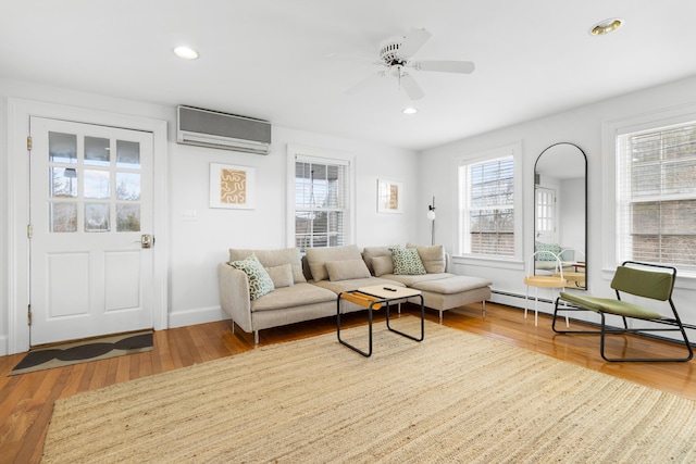 living room with a wall mounted AC, ceiling fan, and wood-type flooring