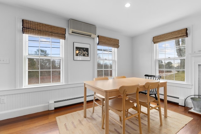 dining space featuring a baseboard radiator, a wall unit AC, and light hardwood / wood-style floors