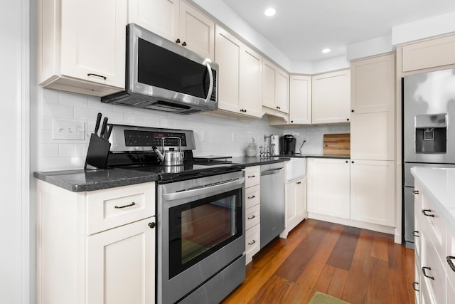 kitchen with dark wood-type flooring, white cabinets, sink, decorative backsplash, and appliances with stainless steel finishes