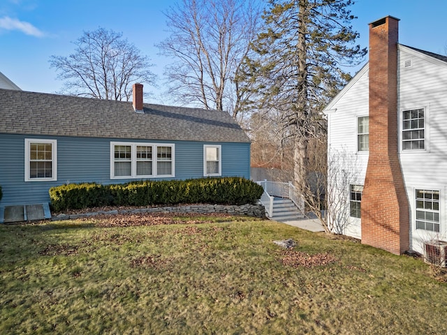 view of side of property featuring a lawn and central AC