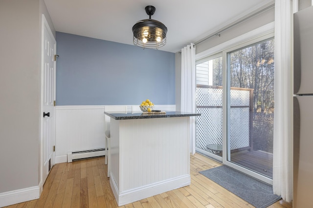 kitchen featuring stainless steel refrigerator, a baseboard radiator, and light wood-type flooring