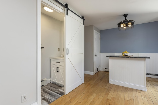 interior space with a barn door, light wood-type flooring, and a baseboard radiator