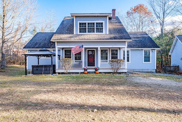 view of front of property featuring a gazebo, covered porch, a hot tub, and a front yard