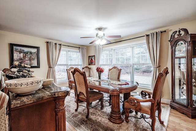 dining room with a baseboard heating unit, light hardwood / wood-style floors, ceiling fan, and a healthy amount of sunlight