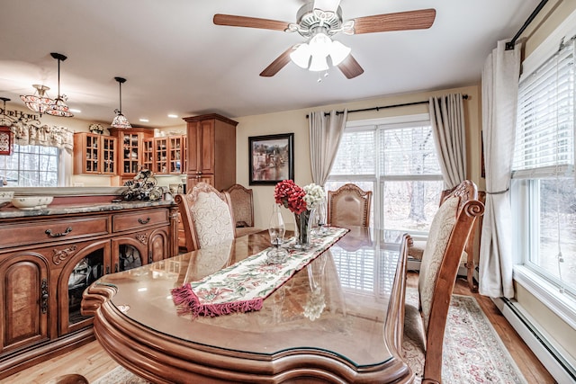 dining room featuring ceiling fan, light hardwood / wood-style flooring, and a baseboard heating unit