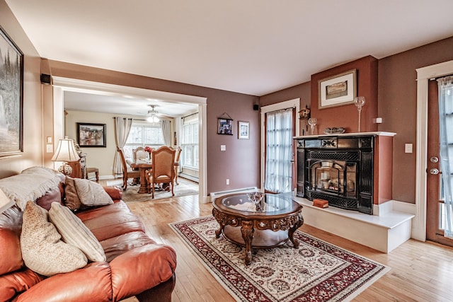 living room featuring baseboard heating, ceiling fan, and light hardwood / wood-style floors