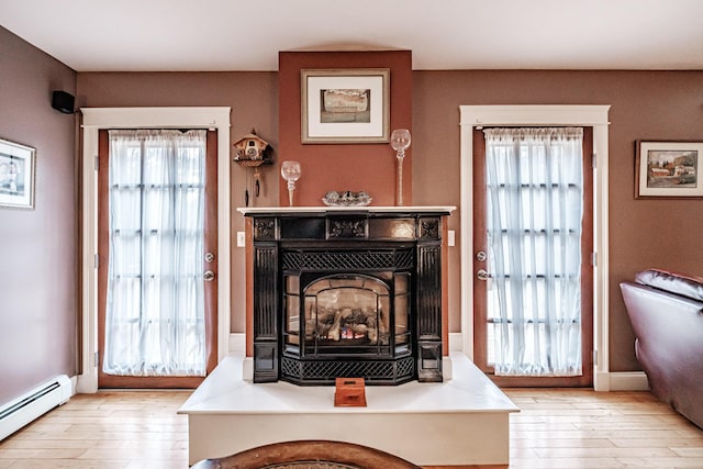 living room with a fireplace, light wood-type flooring, and a baseboard radiator