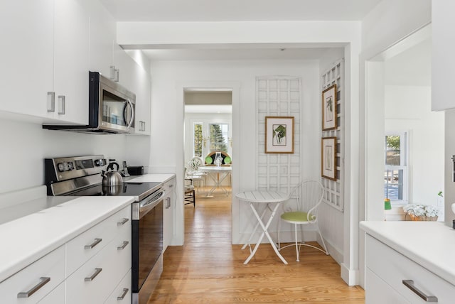 kitchen with white cabinetry, light wood-type flooring, and appliances with stainless steel finishes