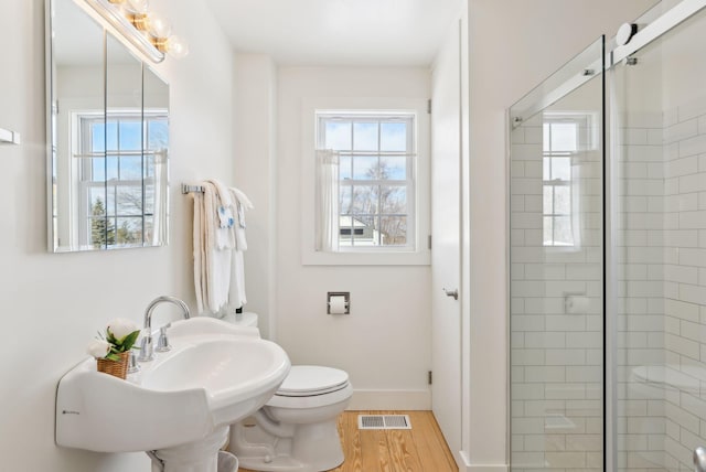 bathroom featuring wood-type flooring, an enclosed shower, plenty of natural light, and toilet