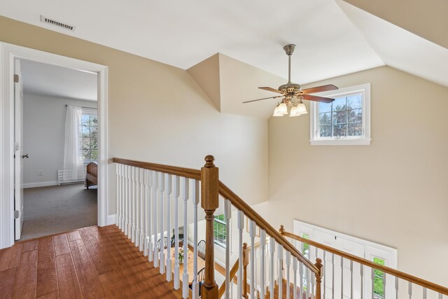 corridor featuring plenty of natural light, wood finished floors, vaulted ceiling, and an upstairs landing