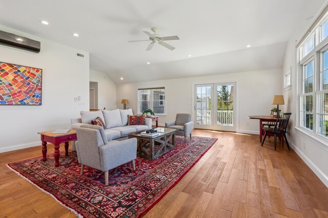 living area with a healthy amount of sunlight, visible vents, wood finished floors, and lofted ceiling