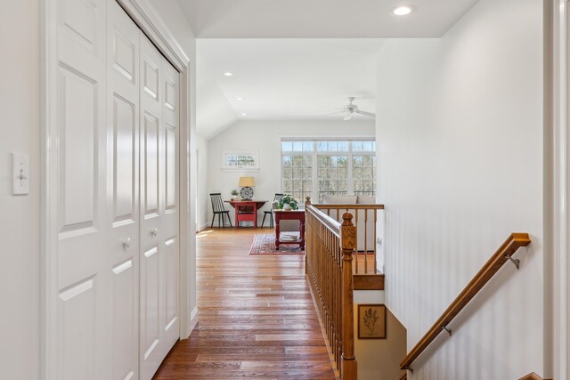 corridor featuring lofted ceiling, recessed lighting, wood finished floors, and an upstairs landing
