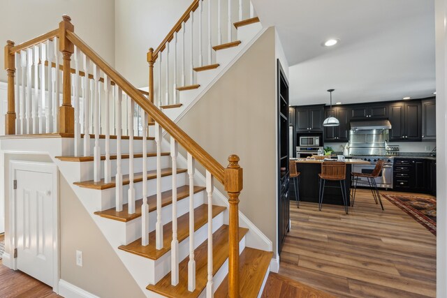 staircase with baseboards, recessed lighting, and wood finished floors