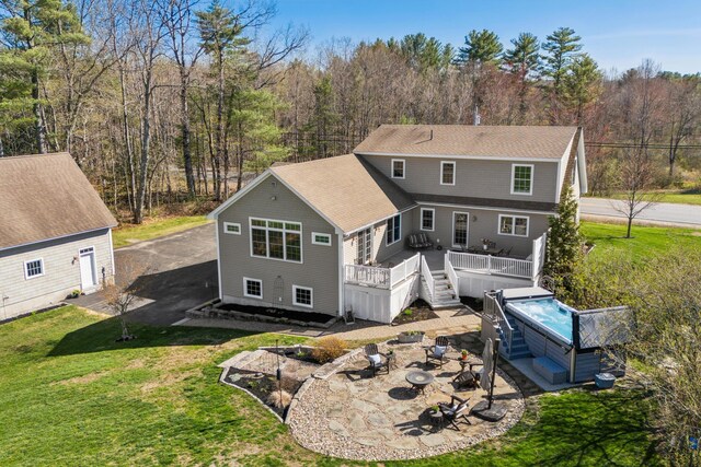 back of property with roof with shingles, an outdoor fire pit, a deck, a patio area, and a yard
