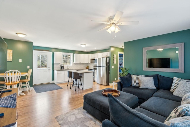 living room with ceiling fan, light hardwood / wood-style flooring, and sink