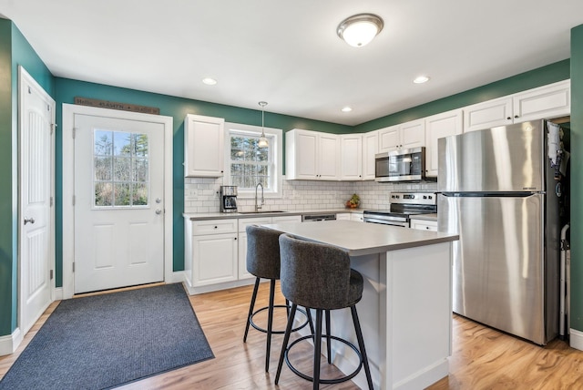 kitchen with pendant lighting, a center island, white cabinetry, appliances with stainless steel finishes, and sink