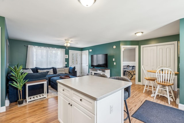 kitchen featuring a center island, white cabinetry, ceiling fan, light hardwood / wood-style floors, and a breakfast bar area