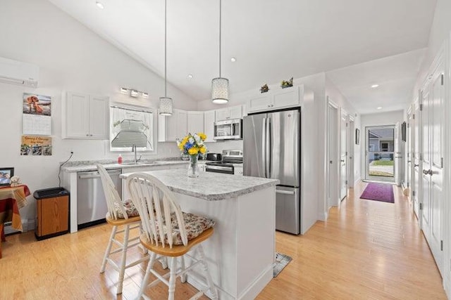 kitchen with white cabinets, a center island, appliances with stainless steel finishes, and pendant lighting