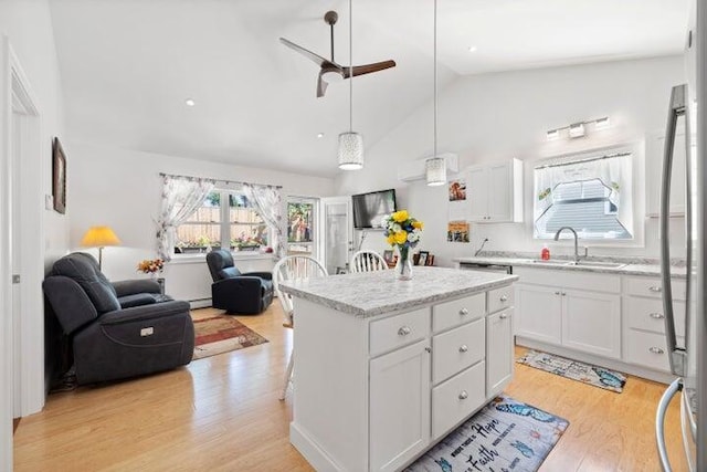 kitchen featuring decorative light fixtures, white cabinetry, a kitchen island, and sink