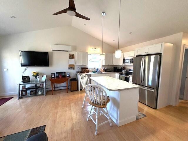 kitchen with stainless steel appliances, decorative light fixtures, an AC wall unit, white cabinets, and a kitchen island