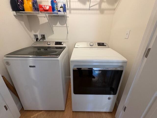 laundry room featuring washer and clothes dryer and light wood-type flooring