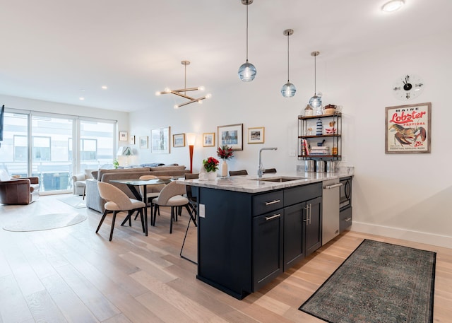 kitchen featuring pendant lighting, light stone countertops, sink, and light hardwood / wood-style flooring