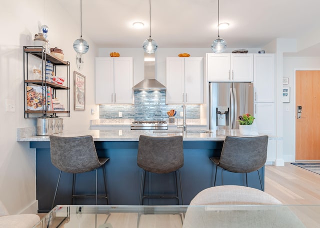 kitchen with tasteful backsplash, wall chimney exhaust hood, decorative light fixtures, stainless steel fridge with ice dispenser, and white cabinetry