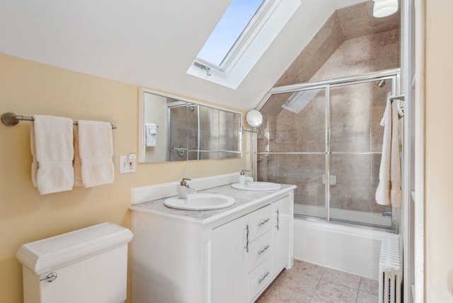 full bathroom with radiator heating unit, combined bath / shower with glass door, lofted ceiling with skylight, tile patterned floors, and vanity