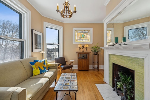 living area with a tile fireplace, light hardwood / wood-style flooring, ornamental molding, and a healthy amount of sunlight