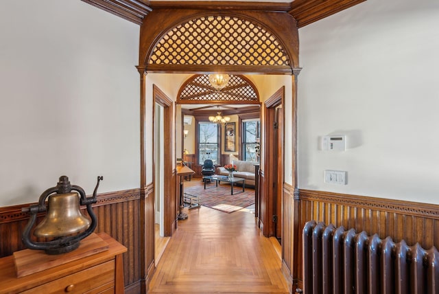 corridor with light parquet floors, radiator heating unit, and a notable chandelier