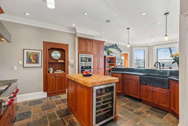 kitchen featuring beverage cooler, wooden counters, sink, hanging light fixtures, and stainless steel microwave