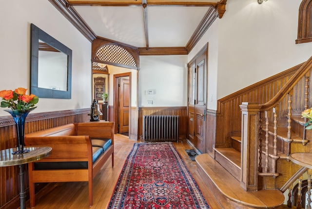 interior space with radiator heating unit, crown molding, and light wood-type flooring