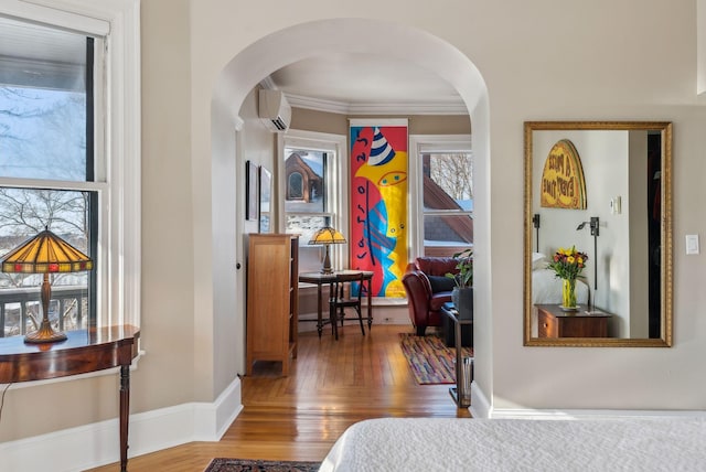 bedroom featuring crown molding, hardwood / wood-style floors, and an AC wall unit