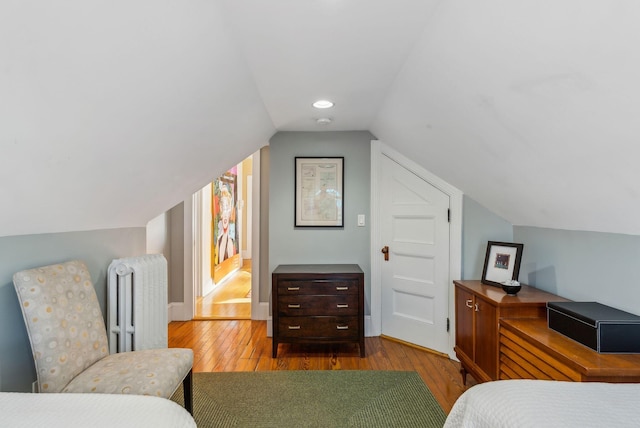 bedroom featuring light hardwood / wood-style floors, radiator, and vaulted ceiling