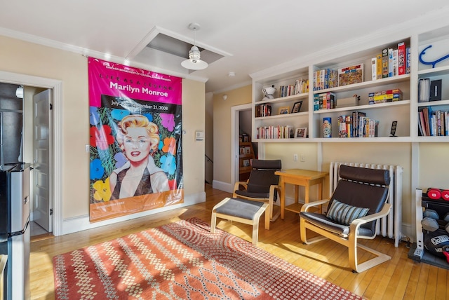 living area featuring hardwood / wood-style flooring and crown molding