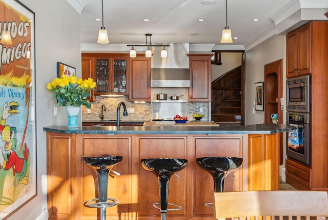 kitchen with decorative light fixtures, crown molding, a breakfast bar area, and appliances with stainless steel finishes