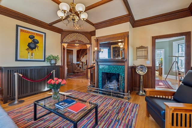 living room featuring a notable chandelier, hardwood / wood-style floors, ornamental molding, and a fireplace