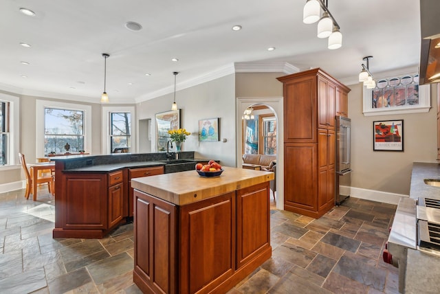 kitchen featuring a center island, sink, decorative light fixtures, kitchen peninsula, and butcher block countertops