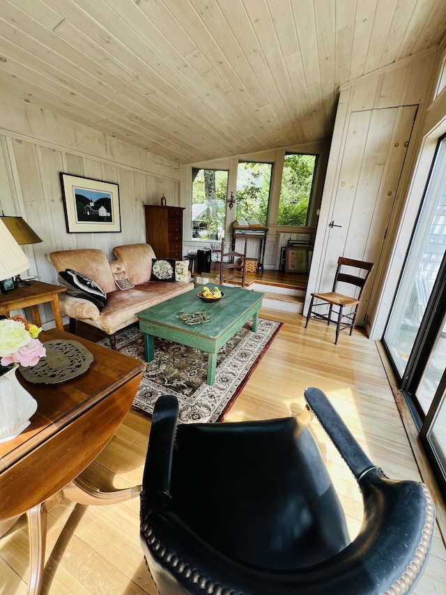 living room with wood walls, light hardwood / wood-style flooring, wooden ceiling, and lofted ceiling