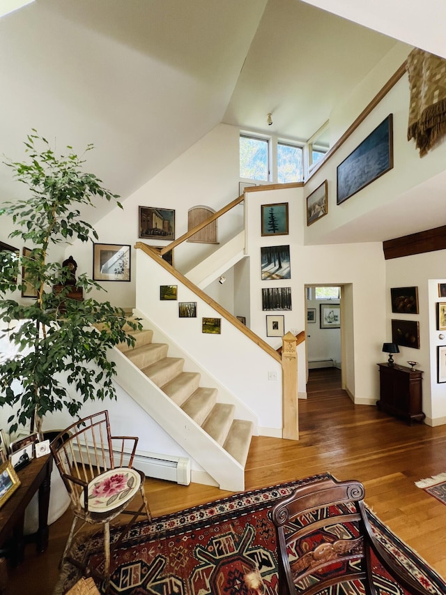 stairway with hardwood / wood-style floors and high vaulted ceiling