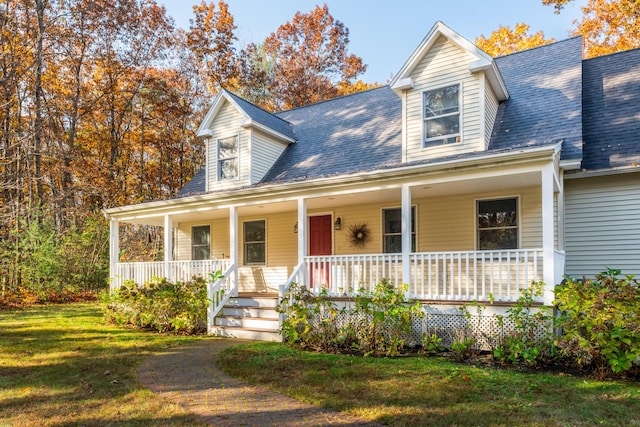 new england style home featuring covered porch and a front lawn