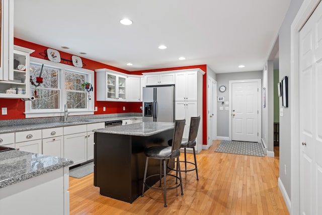 kitchen featuring a kitchen island, stainless steel appliances, light stone countertops, and white cabinets