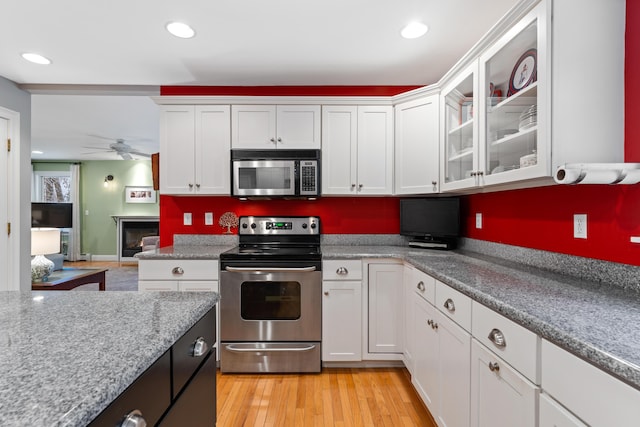 kitchen with appliances with stainless steel finishes, ceiling fan, and white cabinets