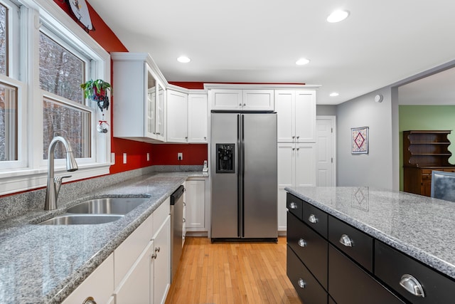 kitchen featuring light stone counters, stainless steel appliances, light wood-type flooring, white cabinets, and sink