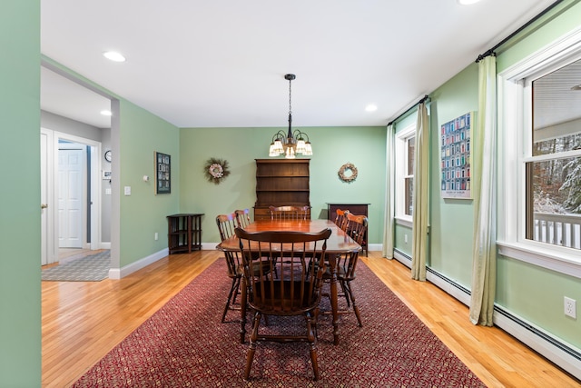 dining area with baseboard heating, hardwood / wood-style floors, and a chandelier