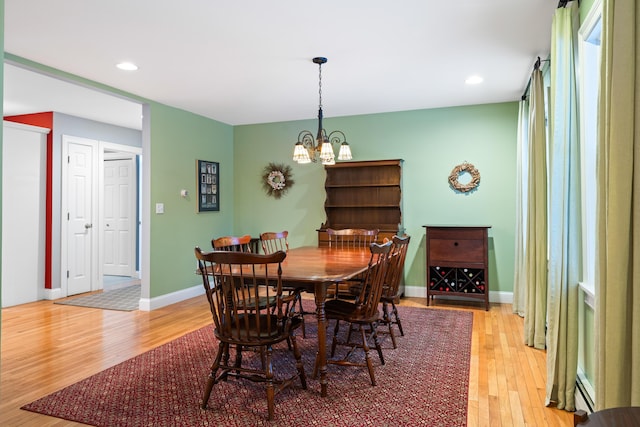 dining space featuring a baseboard radiator, a chandelier, and light hardwood / wood-style flooring