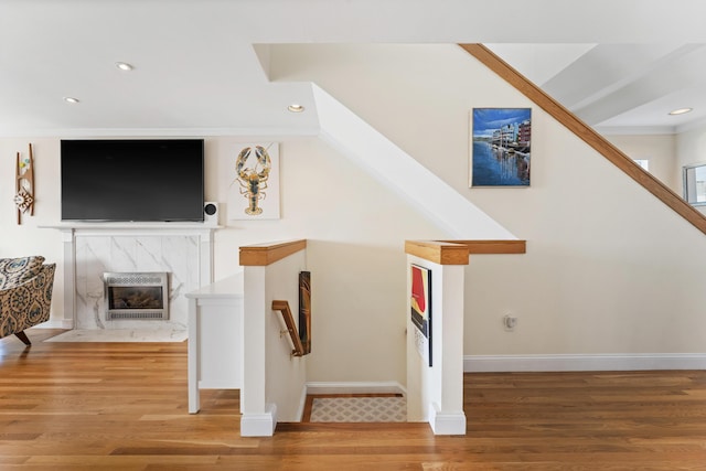 stairs featuring hardwood / wood-style floors, a premium fireplace, and crown molding